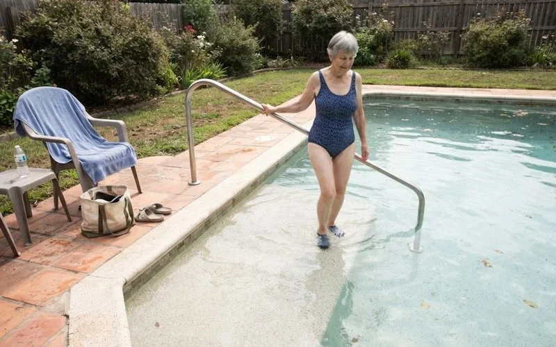 A wide, shallow sun shelf entry point built into the side of a residential pool, offering a step-free way into the water